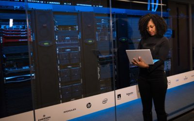 Woman with laptop standing in front of data centre