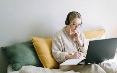Woman working remotely on her laptop in bed